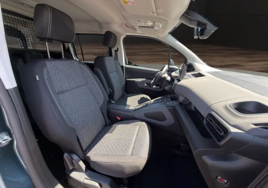 Vue intérieure côté droit du Peugeot Rifter 2026 avec sièges tissu gris et tableau de bord moderne noir.