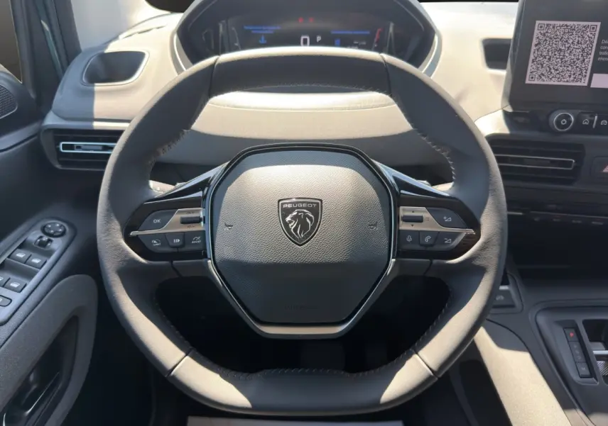Vue rapprochée du volant cuir multifonctions du Peugeot Rifter 2026 avec tableau de bord et écran tactile visibles.