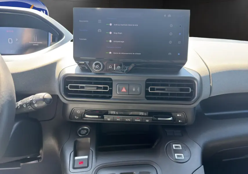 Vue intérieure du tableau de bord du Peugeot Rifter bleu 2026, avec écran tactile central et commandes climatisation visibles.