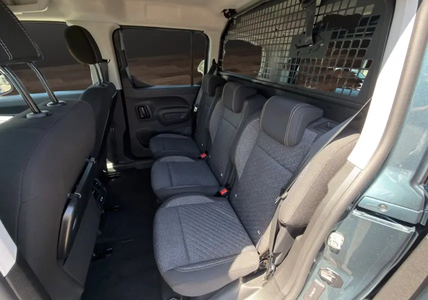 Vue intérieure côté droit des sièges arrière gris foncé du Peugeot Rifter bleu avec séparation grillagée vers le coffre.