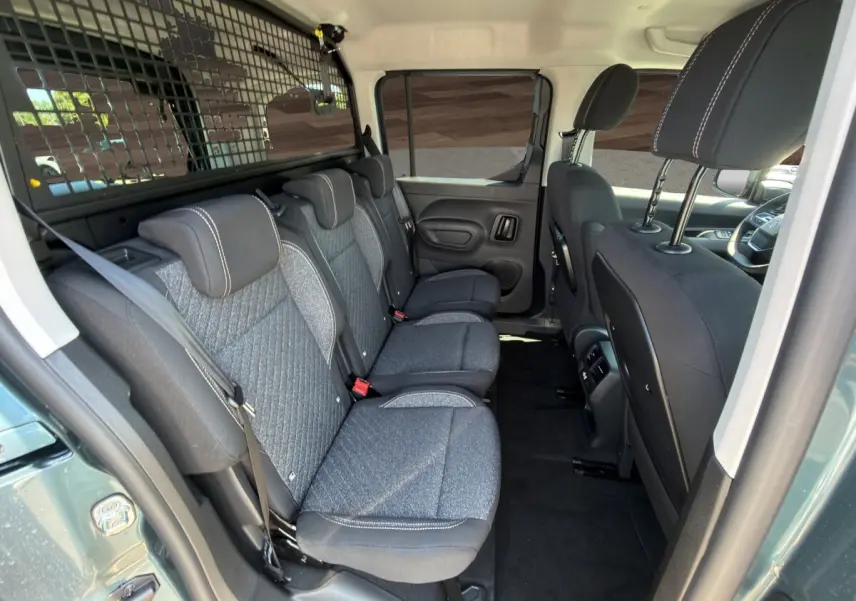 Vue intérieure côté droit sur la banquette arrière grise et noire du Peugeot Rifter bleu avec séparation grillagée.