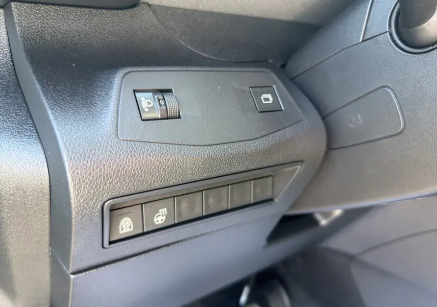 Détail intérieur côté gauche du tableau de bord noir du Peugeot Rifter avec commandes d’éclairage et boutons fonctionnels.