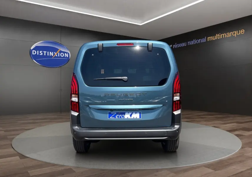 Vue arrière d'un Peugeot Rifter bleu 2026 avec hayon vitré et feux arrière verticaux rouges.