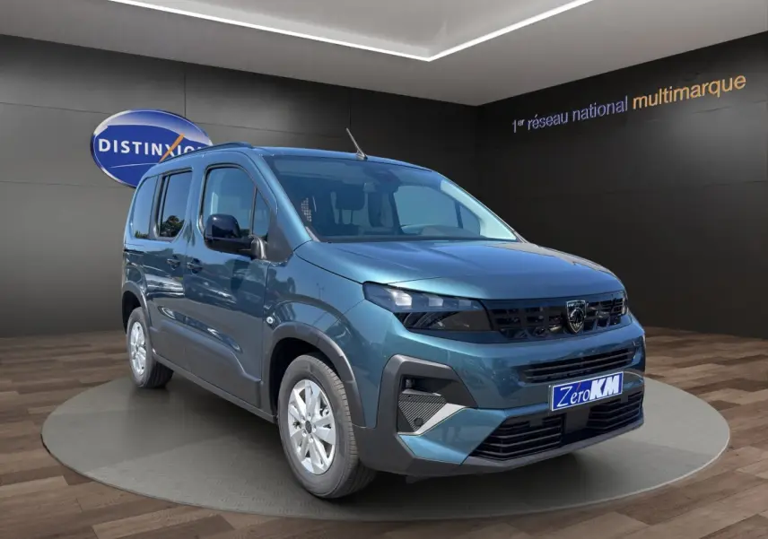 Vue 3/4 avant d'un Peugeot Rifter bleu 2026 en showroom, avec calandre noire et jantes argentées.