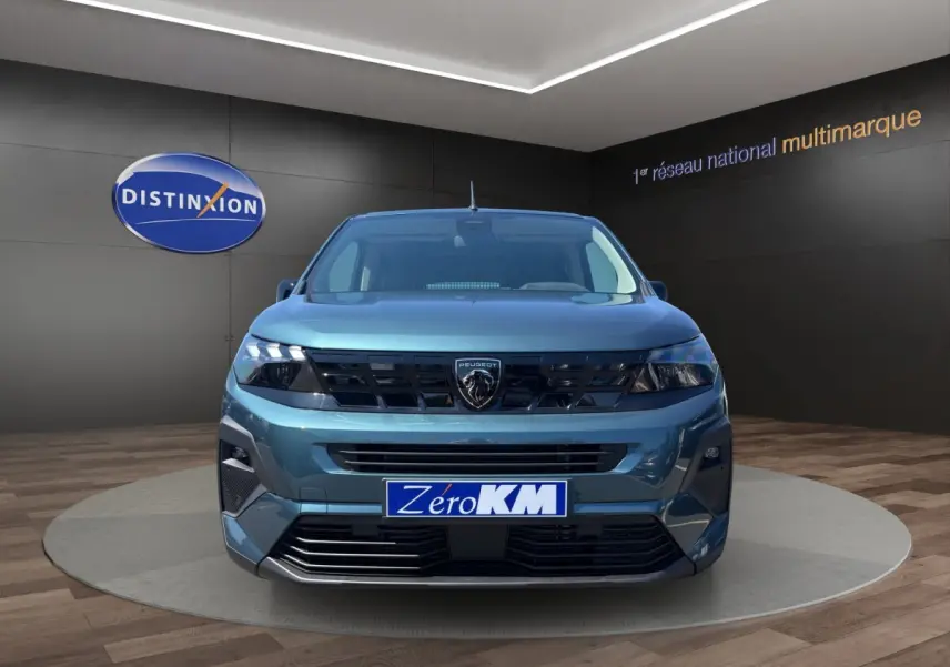Vue frontale d'un Peugeot Rifter bleu métallisé 2026 avec calandre noire et logo lion central bien visible.