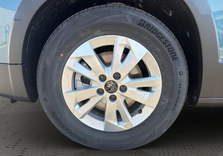 Gros plan sur la roue avant gauche d’un Peugeot Rifter bleu, jante alliage argent avec logo Peugeot central.