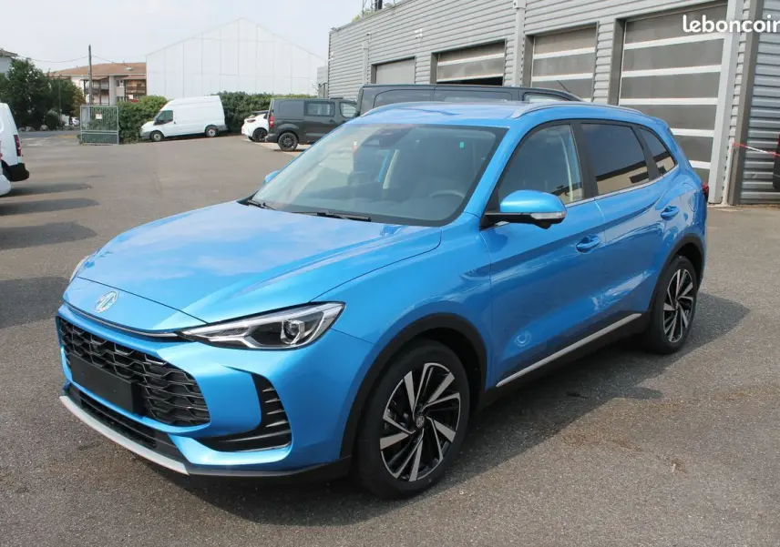 MG ZS 1.5 hybrid bleu en 3/4 avant droit avec jantes alliage et vitres arrière surteintées.