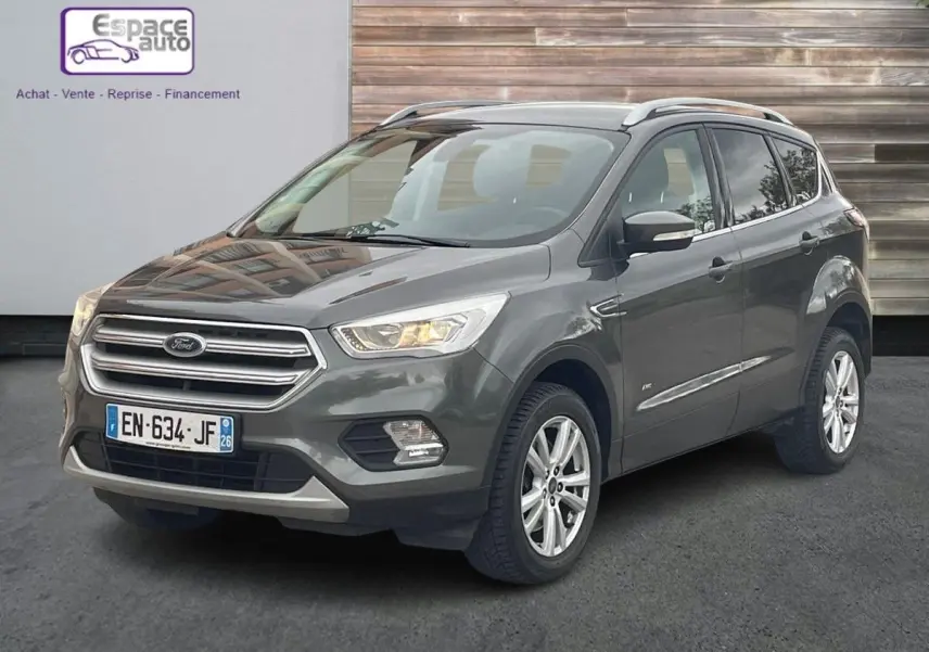 Ford Kuga gris en 3/4 avant droit, SUV compact avec calandre chromée et jantes alliage visibles.