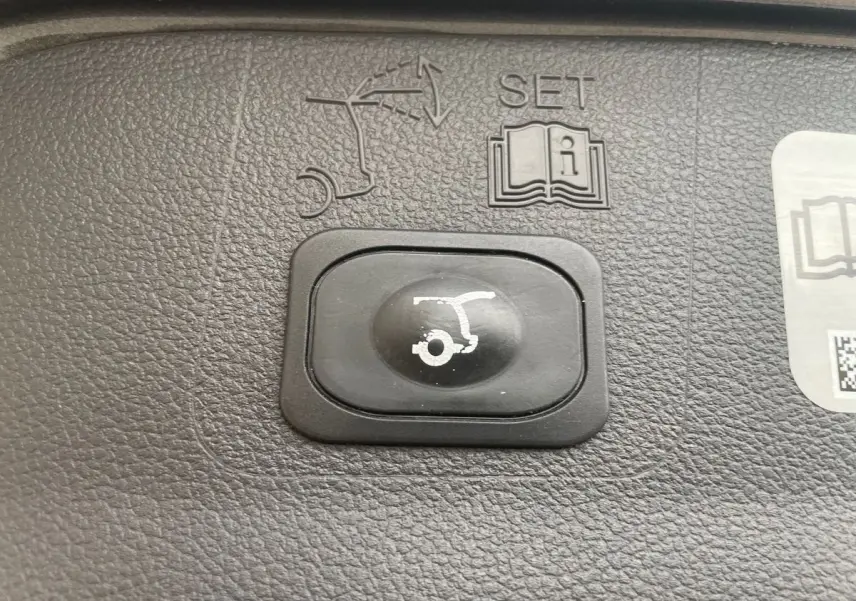 Bouton noir de commande d'ouverture du hayon sur tableau de bord texturé d'un Ford Kuga gris 2017.