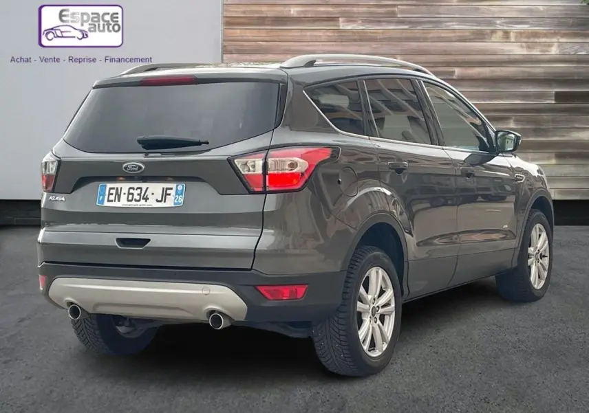 Vue 3/4 arrière droite d'un Ford Kuga gris 2017 avec double sortie d'échappement et vitres teintées.