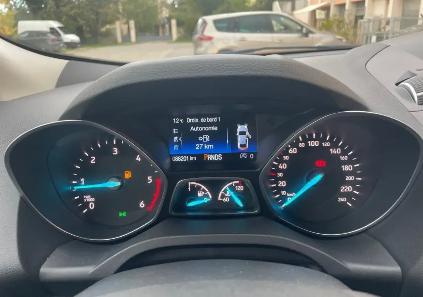 Vue rapprochée du tableau de bord du Ford Kuga gris 2017, affichant les compteurs et l'écran digital central.