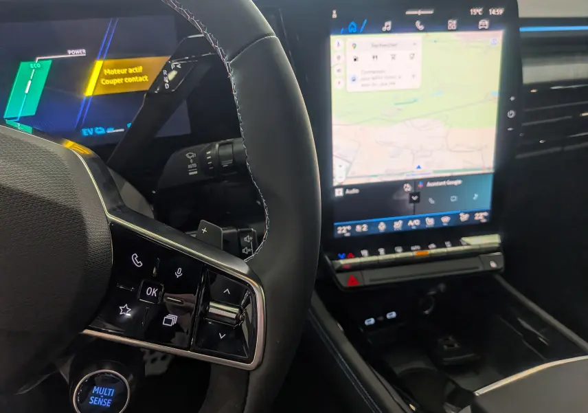 Vue intérieure du tableau de bord et volant du Renault Rafale E-TECH gris, avec écran tactile central affichant la navigation.