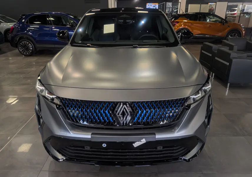 Vue avant rapprochée du Renault Rafale E-TECH gris schiste satin, avec calandre noire et détails bleus lumineux.