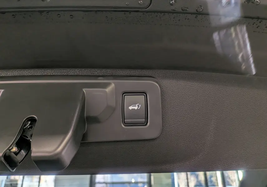 Bouton d'ouverture électrique du hayon sur le bord intérieur du coffre d'une Renault Rafale gris Schiste Satin.