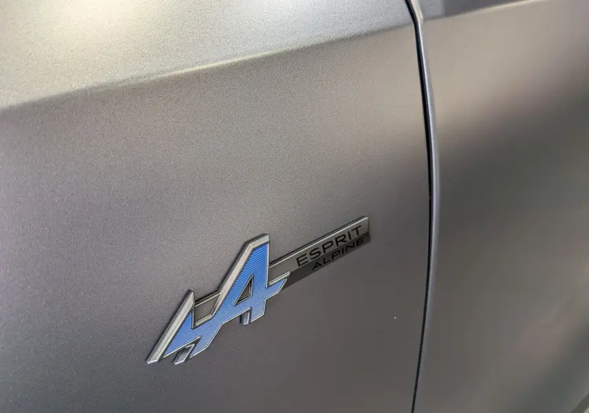 Gros plan sur l’écusson Esprit Alpine bleu sur la porte gris schiste satin du Renault Rafale E-TECH 2025.