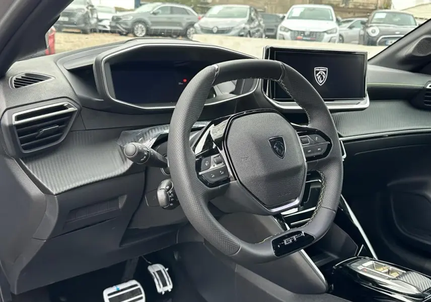 Vue intérieure du poste de conduite de la Peugeot 208 Hybrid GT 2025, avec volant compact GT et écran tactile central.