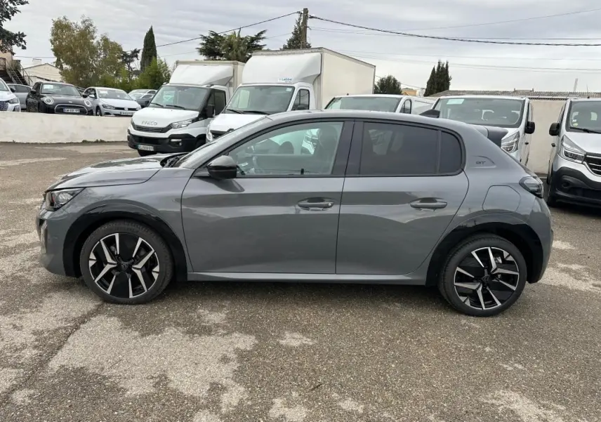 Profil droit d'une Peugeot 208 Hybrid 110 e-DCS6 GT gris, avec jantes alliage 17 pouces et toit noir.