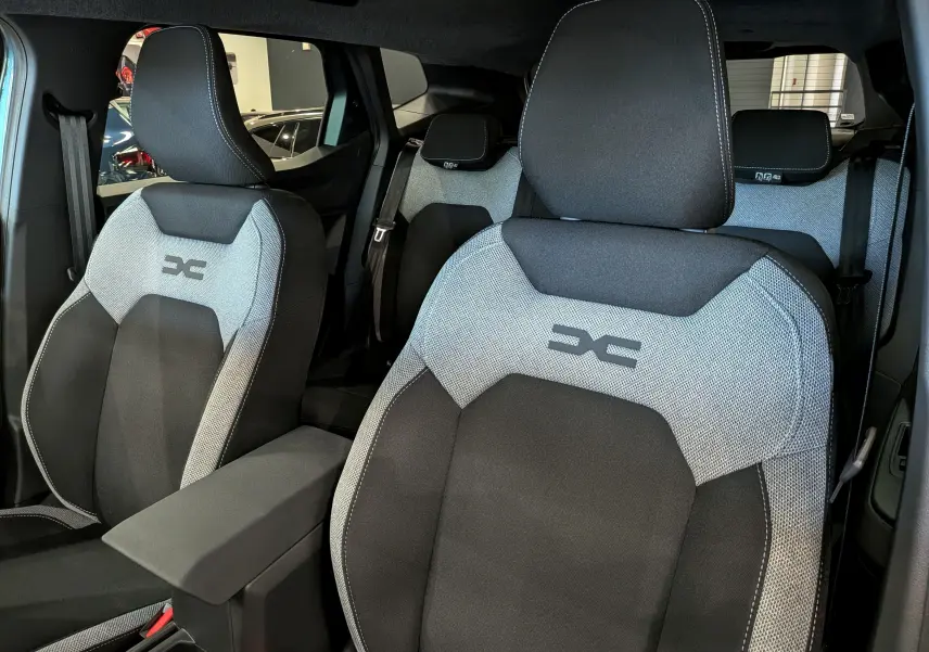 Vue intérieure rapprochée des sièges avant en tissu gris et noir du Dacia Duster Hybrid-G 150 CH 4x4 2026.
