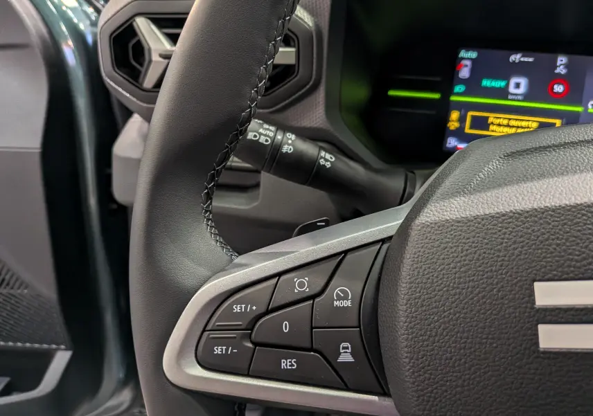 Gros plan sur le volant côté gauche du Dacia Duster Hybrid-G 150 CH 4x4 2026 avec commandes multifonctions et tableau de bord numérique.