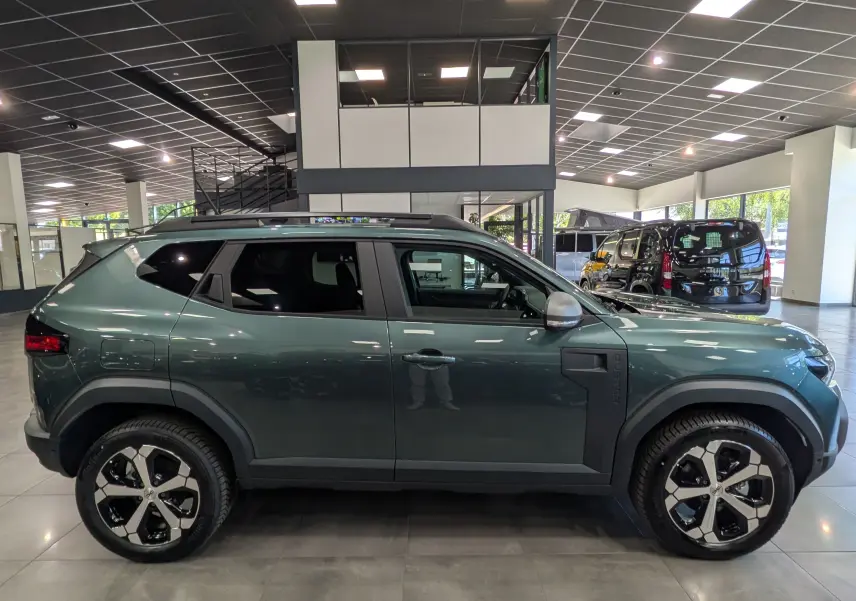 Vue de profil côté gauche du Dacia Duster Hybrid-G 150 CH 4x4 en Vert Cèdre, avec jantes bi-ton et détails noirs contrastants.
