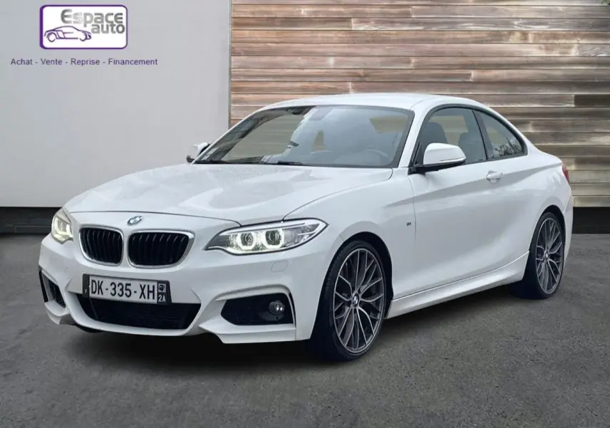 BMW Série 2 Coupé 220d M Sport blanc en 3/4 avant droit, avec phares allumés et jantes alliage distinctives.