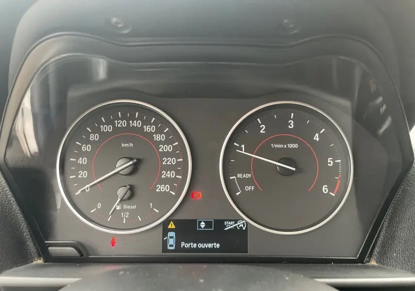 Vue rapprochée du tableau de bord de la BMW Série 2 Coupé F22 blanche, affichant le compteur et le témoin "Porte ouverte".