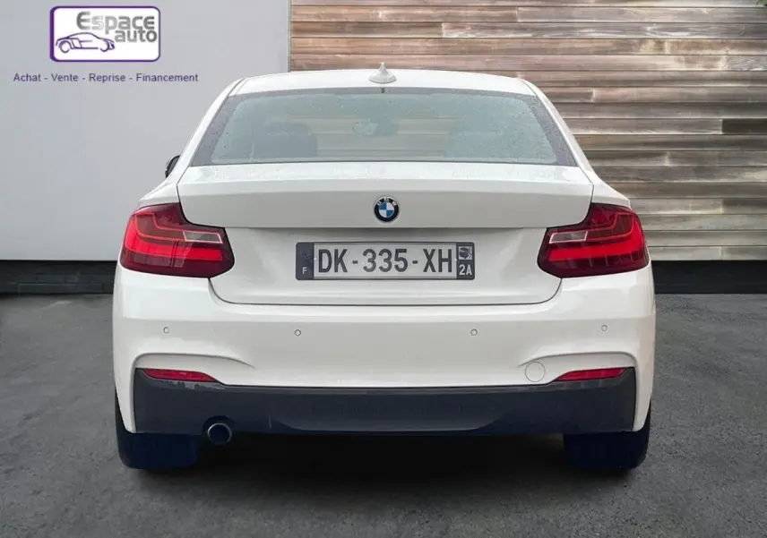 Vue arrière d'une BMW Série 2 Coupé F22 blanche, version 220d M Sport, avec feux rouges et échappement visible côté gauche.