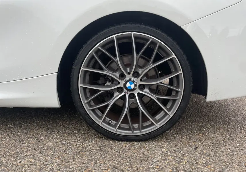 Gros plan sur la roue arrière droite d'une BMW Série 2 Coupé F22 blanche avec jante alliage M Sport multibranches.