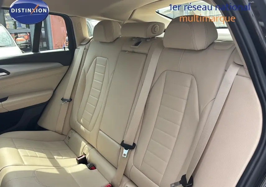 Vue intérieure arrière du BMW X4 XDRIVE 30D 2019 avec sièges en cuir beige lumineux et ceintures de sécurité visibles.