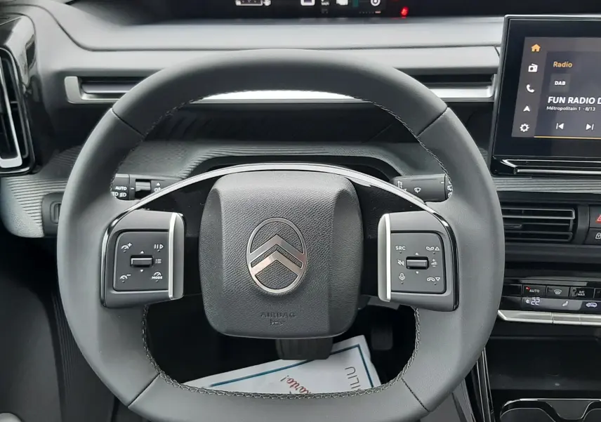 Vue centrée sur le volant noir du Citroën C3 Aircross 2026 gris Mercury, avec tableau de bord digital et écran tactile visible.