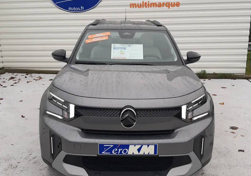 Vue avant d'un Citroën C3 Aircross gris Mercury 2026 avec calandre noire et phares LED distinctifs, stationné devant un mur blanc.