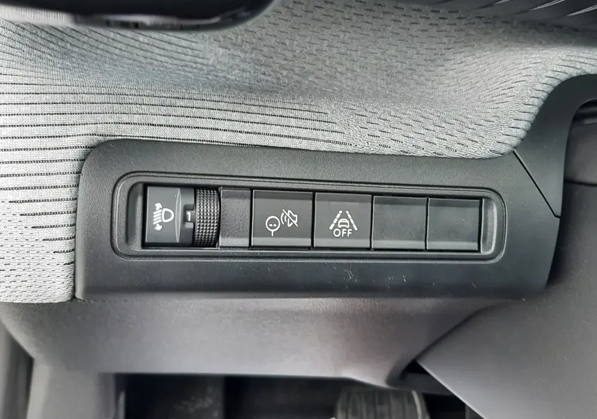 Gros plan sur les commandes d'assistance et réglage des phares du Citroën C3 Aircross 1.2 Hybrid 145 gris Mercury, intérieur côté conducteur.
