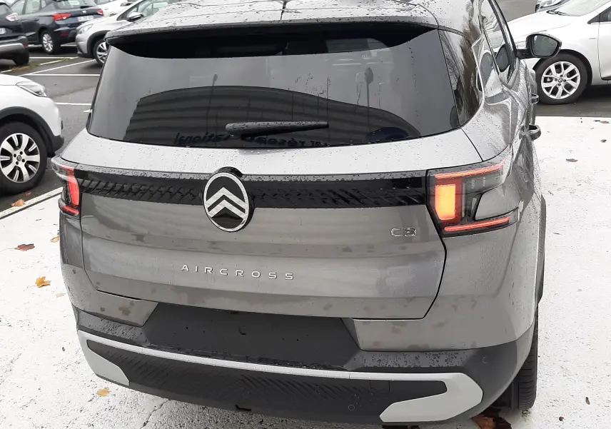 Vue arrière d'un Citroën C3 Aircross gris Mercury 2026 avec feux arrière allumés et vitrage arrière teinté.