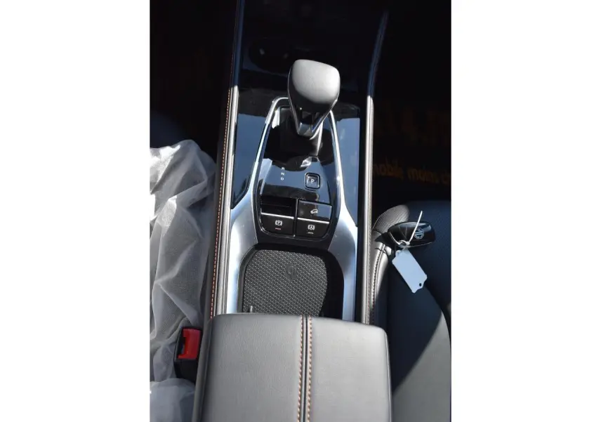 Vue plongeante sur la console centrale noire du MG MOTOR EHS 1.5 Hybrid+ avec levier de vitesse et chargeur à induction.