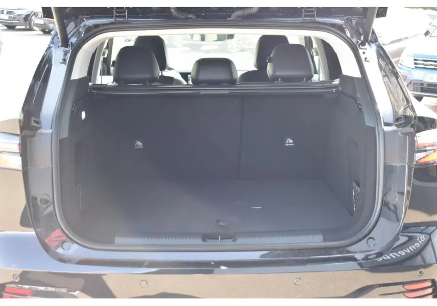 Coffre ouvert vu de l'arrière d'un MG MOTOR EHS noir, montrant l'espace de chargement vide et les sièges arrière.