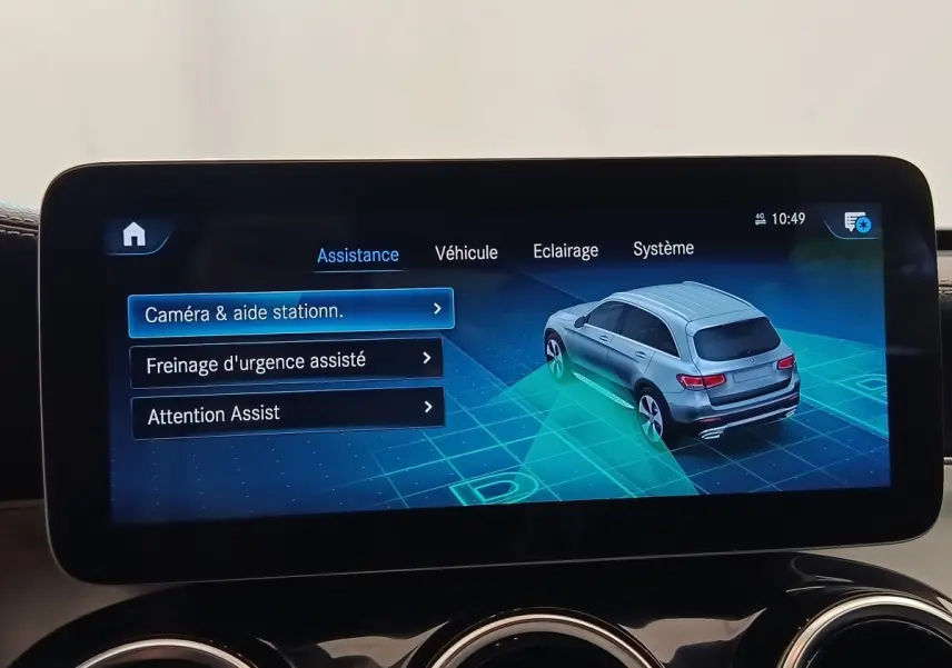 Écran tactile intérieur affichant l'assistance au stationnement avec vue 3/4 arrière d'un SUV Mercedes GLC gris.