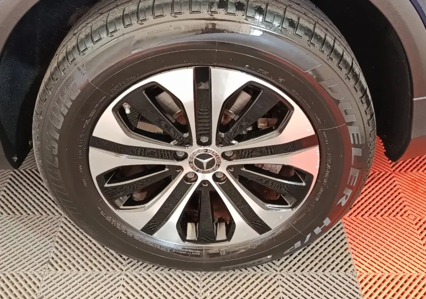 Gros plan sur la roue avant droite du Mercedes GLC bleu, jante alliage bicolore et pneu Bridgestone Dueler.