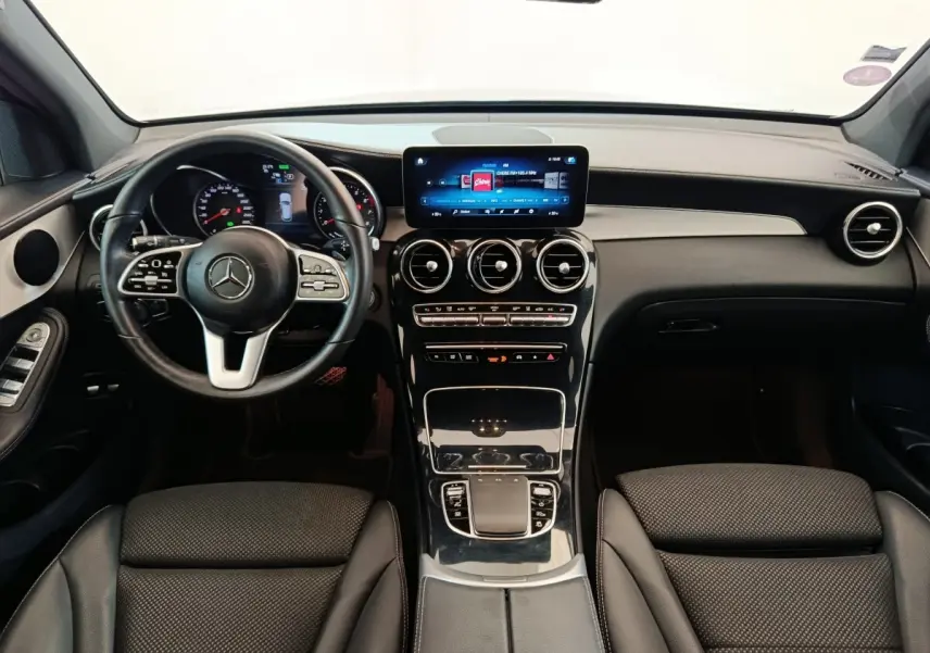 Vue intérieure avant du Mercedes GLC 300 hybride rechargeable 2022, tableau de bord noir avec écran tactile central lumineux.