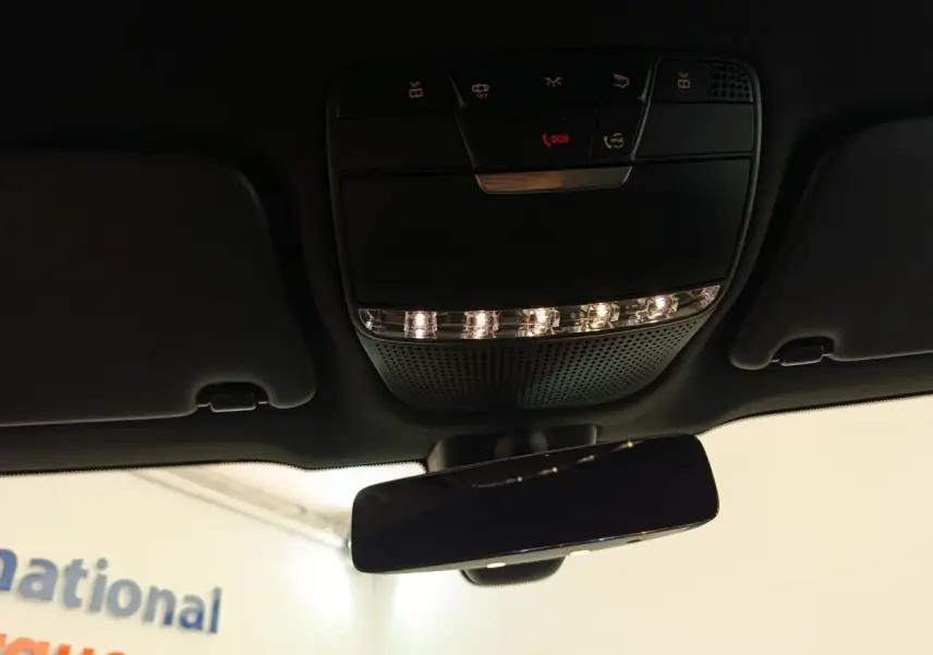 Vue intérieure en contre-plongée du plafonnier noir avec commandes et rétroviseur intérieur du Mercedes GLC 300 hybride 2022.