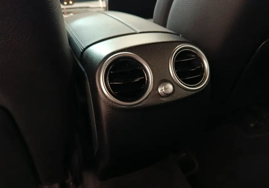 Gros plan sur les aérateurs arrière noirs avec cerclage argenté dans l’habitacle du Mercedes GLC 300 hybride rechargeable bleu.