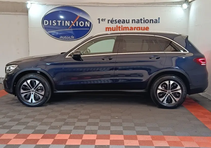 Profil droit d'un Mercedes GLC 300 DE Business Line 4MATIC bleu, avec jantes alliage et toit chromé visible en intérieur showroom.