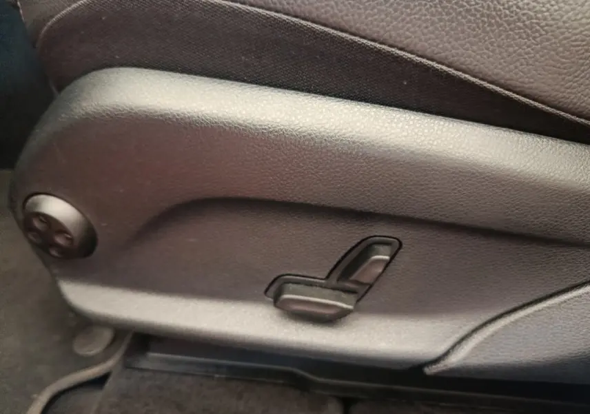 Commande de réglage électrique du siège avant en cuir marron d’un Mercedes GLC bleu, vue latérale rapprochée.