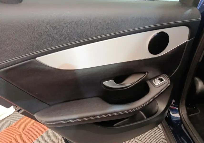 Gros plan sur la porte intérieure côté gauche d’un Mercedes GLC 300 DE Business Line bleu, avec insert aluminium et commande vitre.