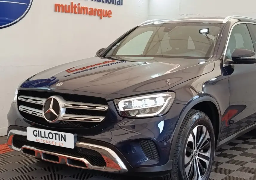 Vue 3/4 avant d’un Mercedes GLC 300 DE Business Line 4MATIC bleu avec calandre chromée et phares LED allumés.