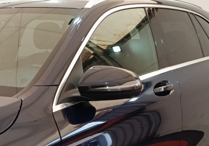 Détail du côté gauche d’un Mercedes GLC bleu avec rétroviseur et poignée de porte visibles.