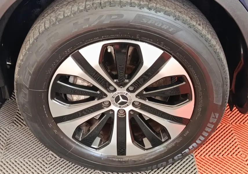 Gros plan sur la jante alliage noir et argent avec logo Mercedes d’un Mercedes GLC bleu, vue latérale.