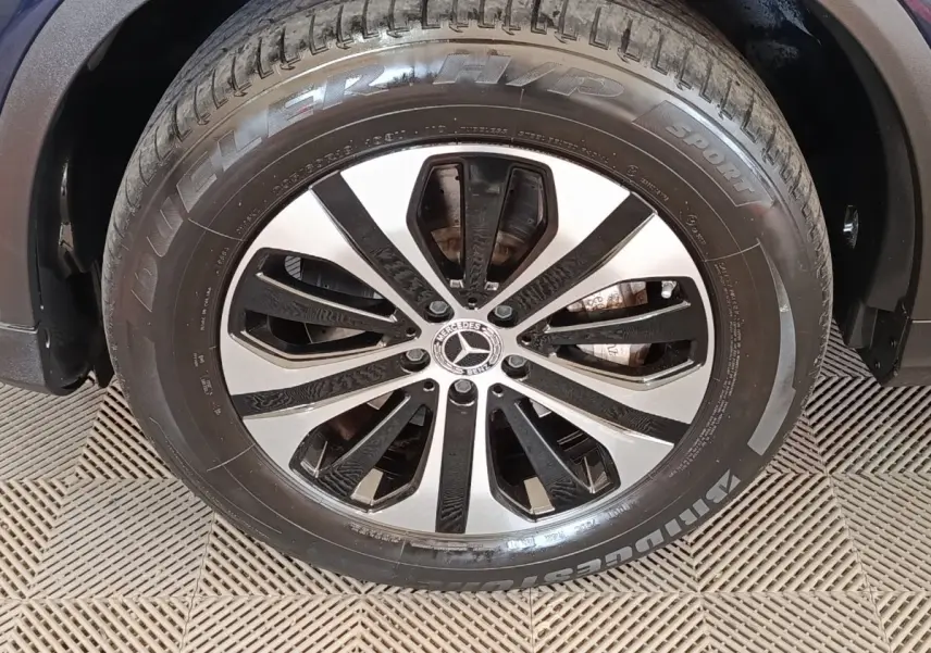 Gros plan sur la roue avant droite d’un Mercedes GLC bleu, avec jante alliage bicolore et pneu Bridgestone.