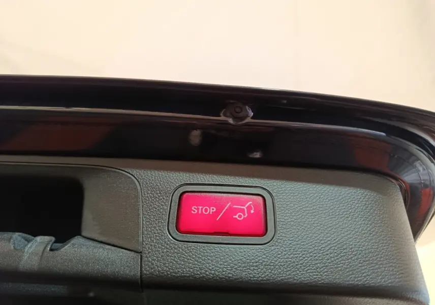 Bouton rouge stop ouverture coffre sur la partie intérieure du hayon d’un Mercedes GLC bleu hybride rechargeable.