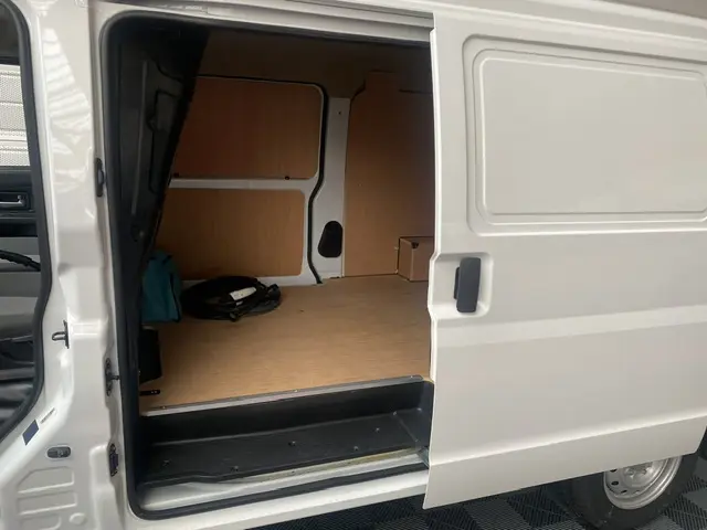 Vue latérale droite du fourgon blanc DFSK EC35 SERES ECOCITY 11900 HT 2023 avec porte coulissante ouverte sur l’espace de chargement en bois.