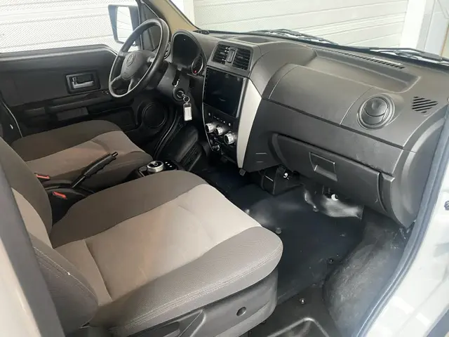 Intérieur côté conducteur du DFSK EC35 blanc 2023, tableau de bord noir avec écran tactile central et volant multifonctions.